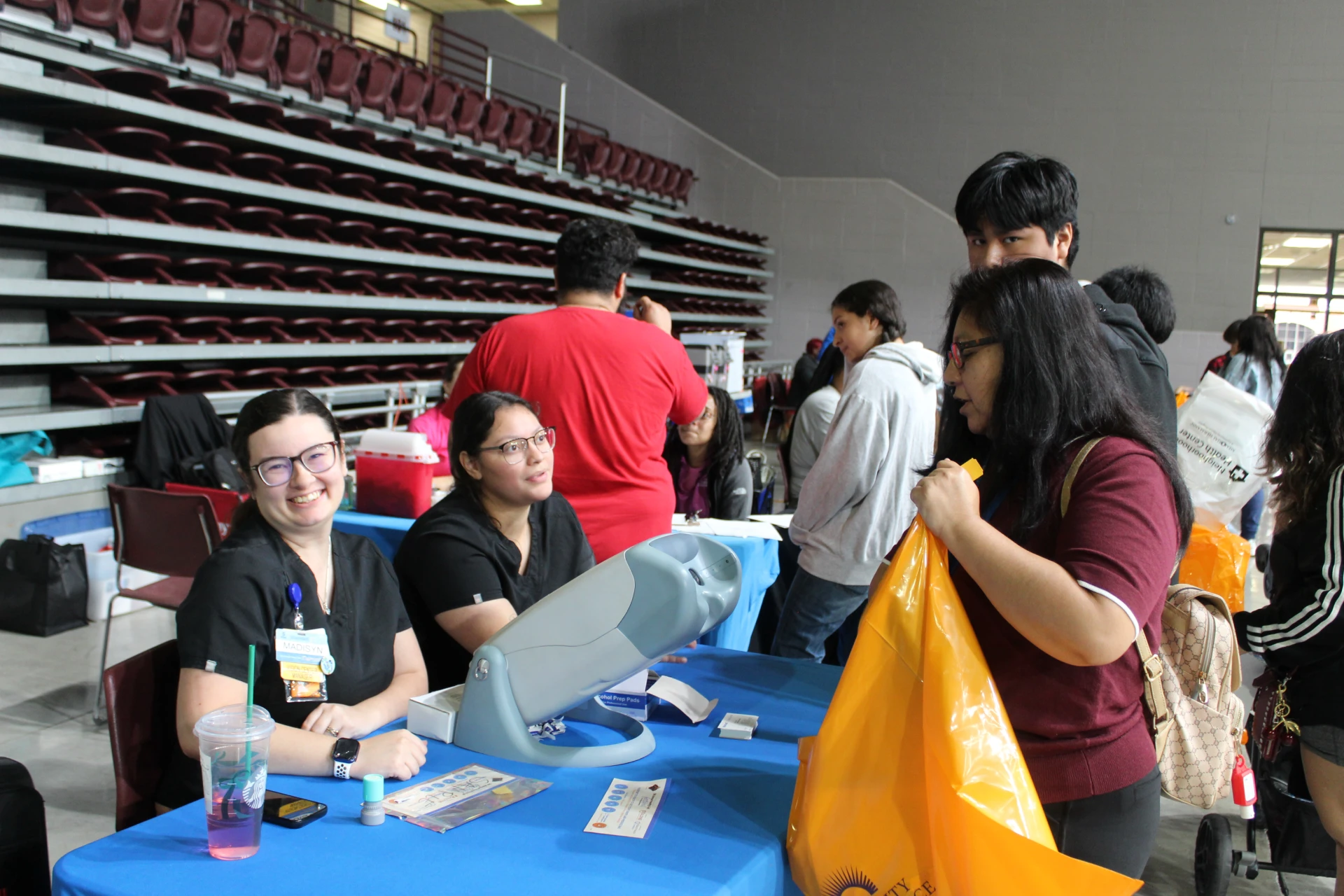 Event staff assisting attendees at a registration or check-in table while a participant holds a bag during the Equality Health Foundation Houston Fall Festival 2026.