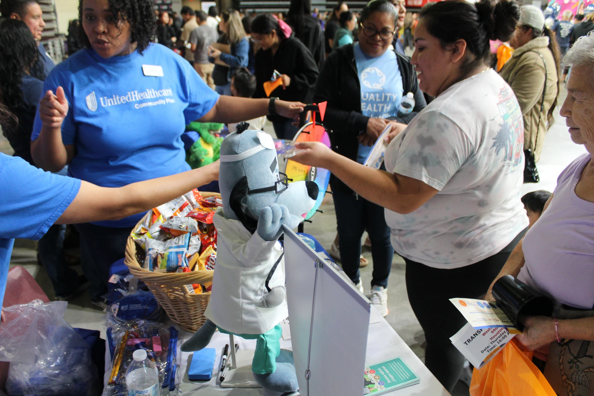 Event staff handing out giveaways and information to attendees at a community booth during the Equality Health Foundation Houston Fall Festival 2026