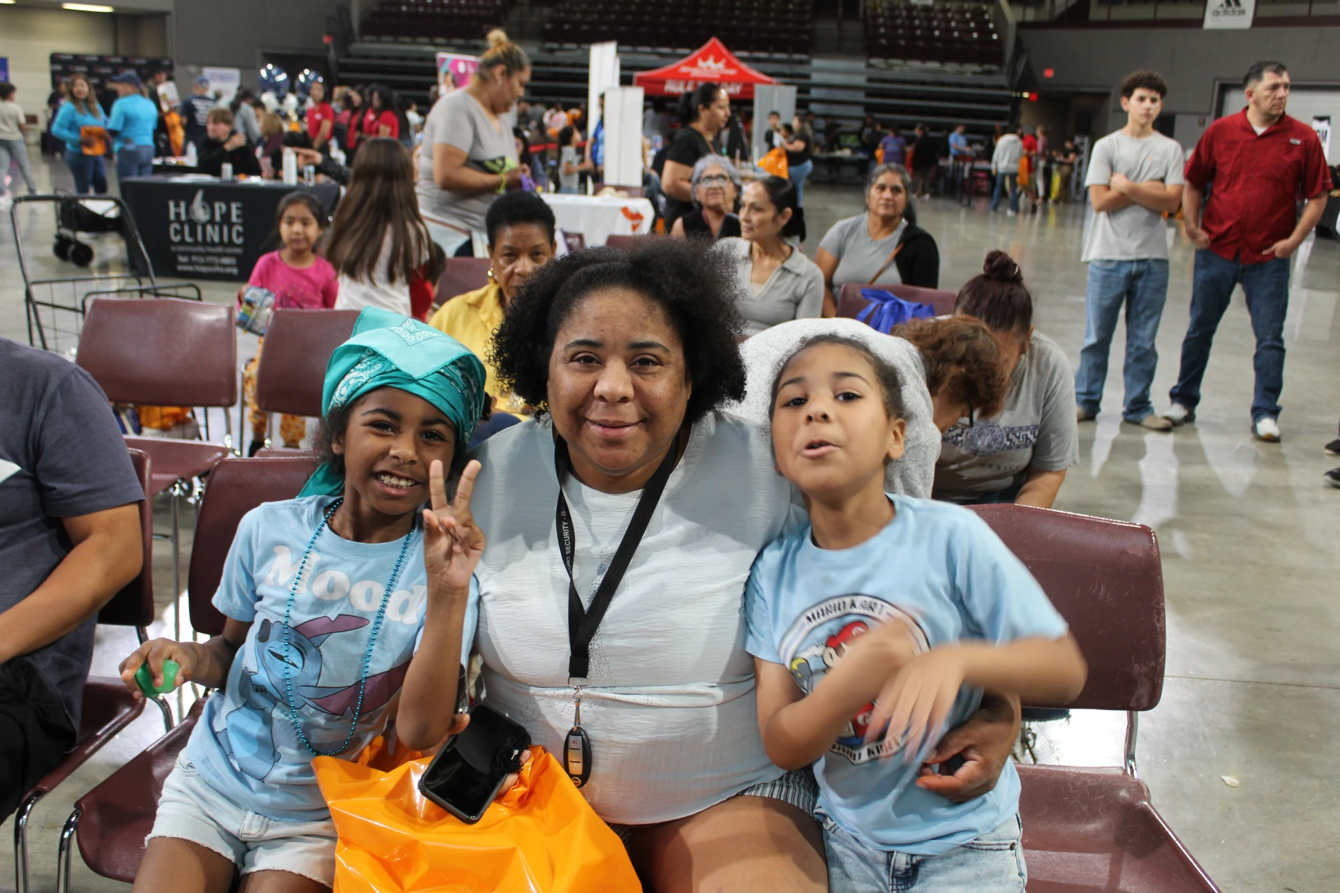 Woman sitting with two children smiling and posing for a photo among event attendees during the Equality Health Foundation Houston Fall Festival 2026.
