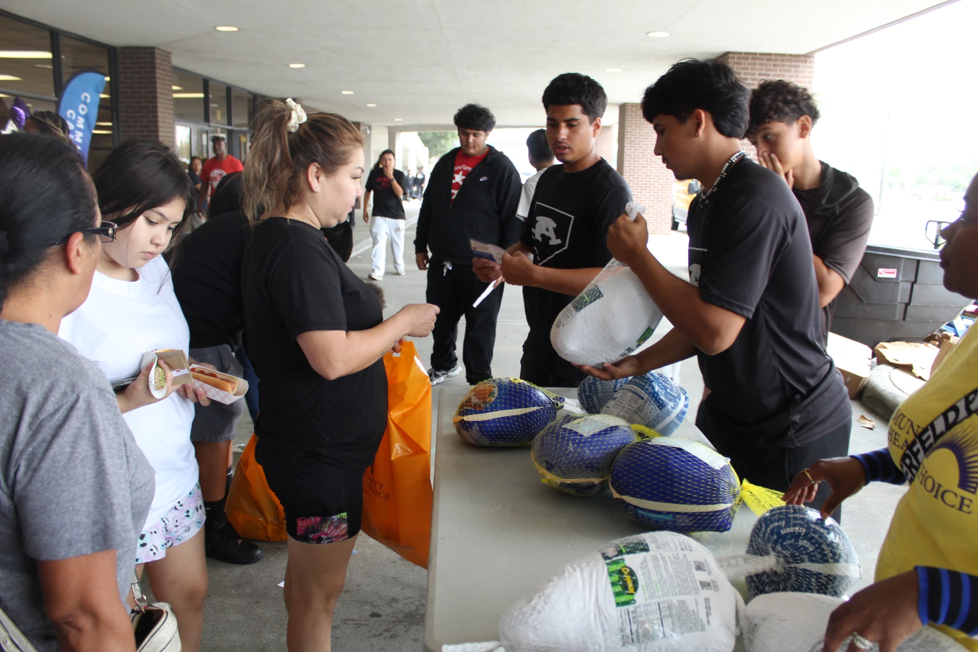 Volunteers and attendees gathered around a table distributing food items during the Equality Health Foundation Houston Fall Festival 2026.