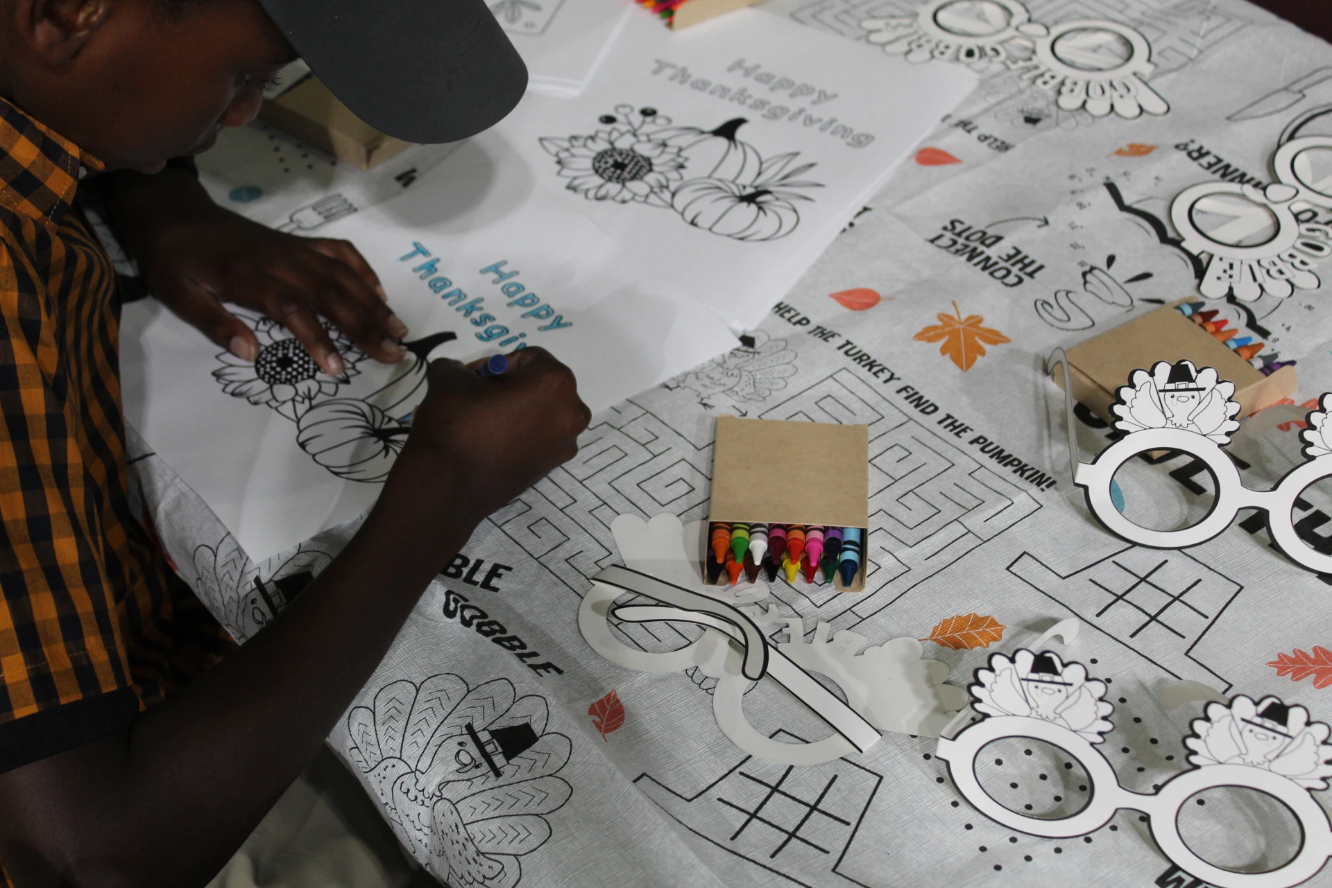 Child coloring a “Happy Thanksgiving” sheet at a table with crayons and fall-themed activity pages during the Equality Health Foundation Houston Fall Festival 2026.